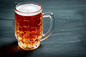 Mug with beer on black background.