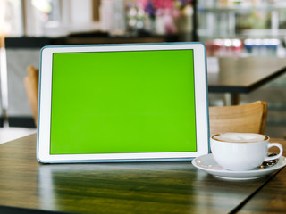 Green screen tablet and coffee mug on table, mock up.