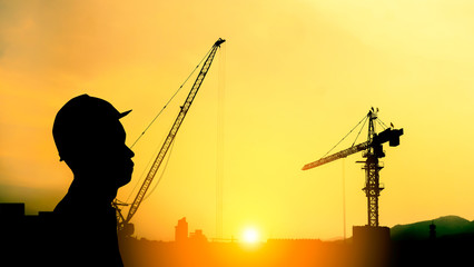 Silhouette engineer standing survey work on construction site and sunset