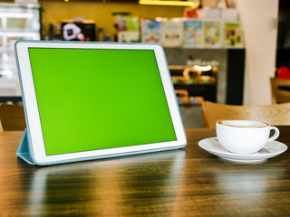 Green screen tablet and coffee mug on table, mock up.