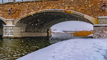 Clear Panorama Snowy trail along lake and passing under a bridge