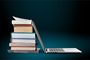 Stack of books with laptop on table