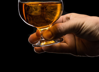 A round glass of whiskey brandy with ice in the men's hand