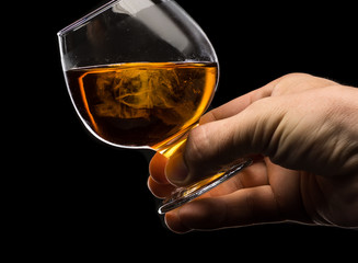 A round glass of whiskey brandy with ice in the men's hand