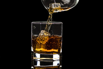Hexagonal glass of whiskey brandy with ice and splashes from falling ice