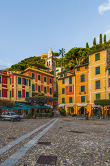 Fototapeta na wymiar Colorful houses of the Piazzetta square and empty outdoor cafe in the coastal italian village Portofino in Liguria region, Italy