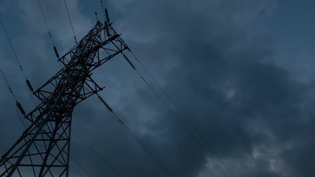 Power transmission lines high voltage electricity grid with cloudy blue sky on background shot in time lapse, fluffy white clouds moving fast. Free space for text title or logo