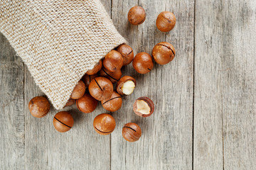 Macadamia nut on a wooden table in a bag, closeup, top view