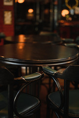 Vintage barrel table with two vintage high chairs, dark interior and dark furniture.