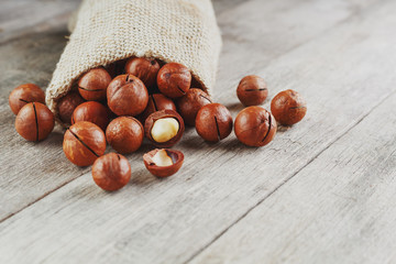 Macadamia nut on a wooden table in a bag, closeup, top view