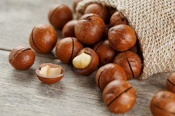Macadamia nut on a wooden table in a bag, closeup, top view