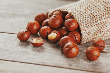 Macadamia nut on a wooden table in a bag, closeup, top view