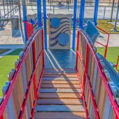 Clear Square Playground equipment with a bridge and slide against vibrant green lawn