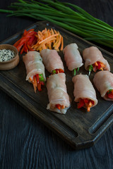 Homemade rolls with fresh chicken breast with greens, carrot slices, bell pepper on a dark cutting board. The concept of healthy homemade food. Dark wooden background.