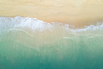 Aerial view of turquoise ocean wave reaching the coastline. Beautiful tropical beach from top view. Andaman sea in Thailand. Summer holiday vacation concept