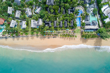 Fototapeta na wymiar Aerial view of resort villa planning with coconut trees, umbrellas and deck chairs on the beach. Beautiful ocean wave reaching coastline from top view. Andaman sea in Thailand. Summer holiday concept