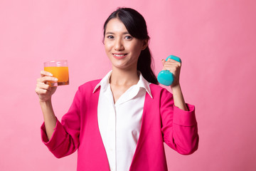 Young Asian woman with dumbbell drink orange juice.