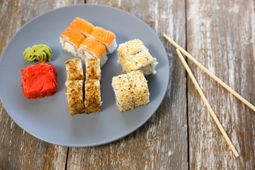 Sushi on the plate with chopsticks on wooden background. Dinner in Japanese style. Healthy food concept. Salmon, wasabi and ginger. Vegetarian.
