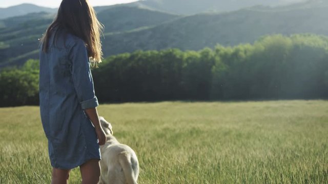 girl standing in field with her dog, dog walks off