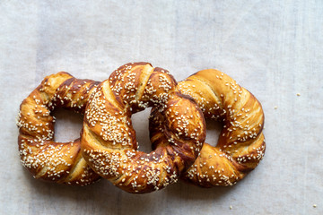 Freshly baked bagels with sesame seeds on a white baking parchment. Top view.