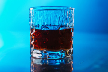 Whisky on lowball glass with ice over reflective surface