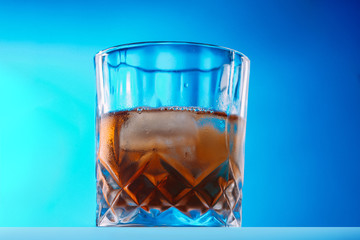 Whisky on lowball glass with ice over reflective surface