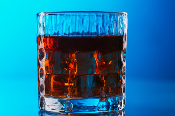 Whisky on lowball glass with ice over reflective surface