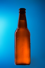 Beer bottle with white belgian ale on blue background