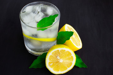  A glass of cold water with about ice, lemon and mint on a blue background