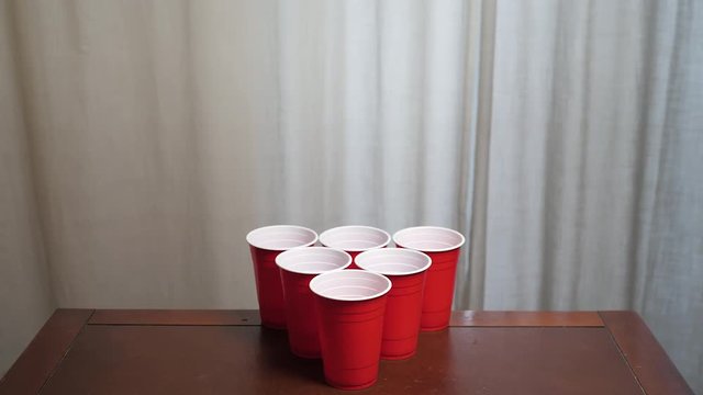POV of playing beer pong, bouncing ball in a red solo cup and then missing a shot