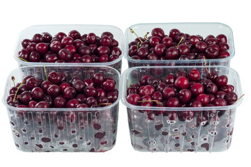 Harvest red sweet cherries in transparent plastic containers isolated on white background.