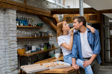 Young couple in love eating pizza in the rustic home