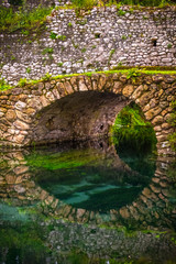 round stone bridge reflected in river water vertical background