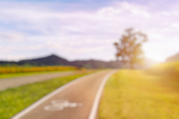Out of Focus of Scenery bicycle lane on a hill with a tree, blue sky and mountain forest background.