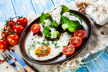 Fried egg with vegetables on wooden table