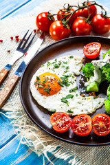 Fried egg with vegetables on wooden table