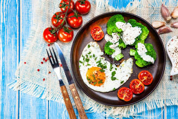Fried egg with vegetables on wooden table