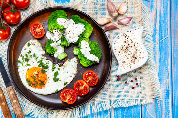 Fried egg with vegetables on wooden table