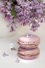 Fototapeta na wymiar Tasty french violet macaroons and lilac flowers