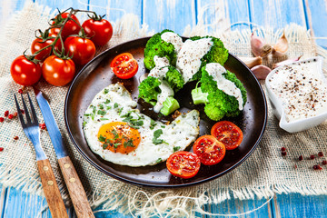 Fried egg with vegetables on wooden table