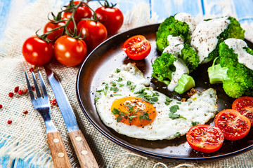 Fried egg with vegetables on wooden table