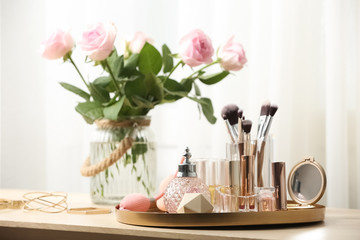 Different makeup products and accessories on dressing table in room interior