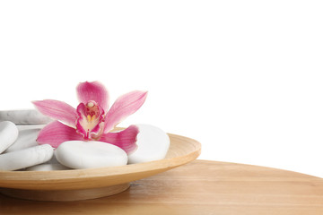 Wooden plate with orchid flower and spa rocks on table against white background. Space for text
