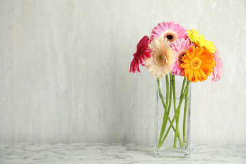 Bouquet of beautiful bright gerbera flowers in vase on marble table against light background. Space for text