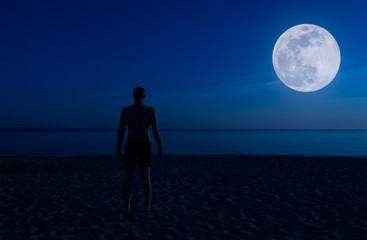 Shirtless man on the beach at night