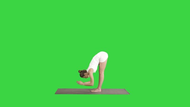 Beautiful model doing yoga exercise standing in Uttanasana with palms at the backs of ankles on a Green Screen, Chroma Key.