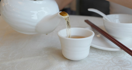 Pouring hot tea into a cup at chinese restaurant