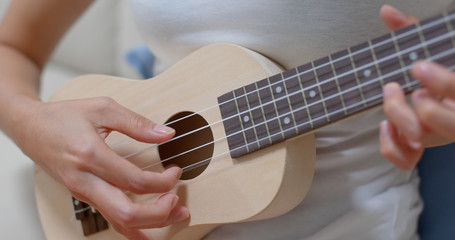 Woman play with ukulele at home