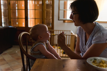 Mom giving food to baby on warm summer afternoon