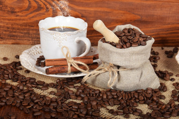 linen bag with coffee beans and a cup of hot coffee